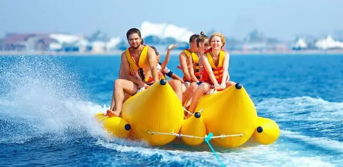 Tourists enjoying banana boat ride in Bali's blue waters โ an exciting activity included in Bali tour packages