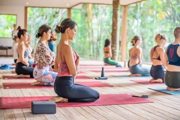 Group of people practicing yoga in an open studio surrounded by nature, showcasing Bali as the Ultimate Destination for Spiritual and Physical wellness.