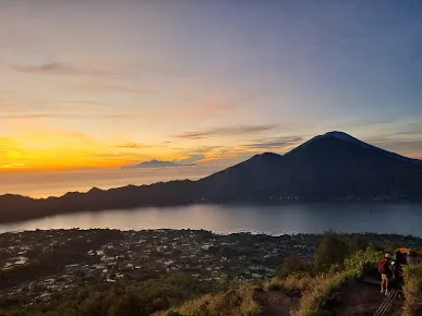 Mount Batur sunrise view with scenic lake and mountains, a must-visit adventure spot included in Bali tour packages.