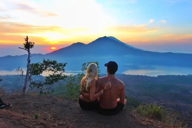 Couple experiencing a transformative journey in Bali at sunrise with scenic mountain view.