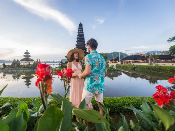 Romantic couple enjoying a transformative journey in Bali amidst temple and vibrant flowers.