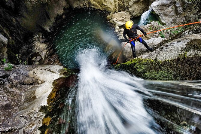 Tourist enjoying canyoning waterfall adventure in Bali with professional guide and stunning jungle surroundings