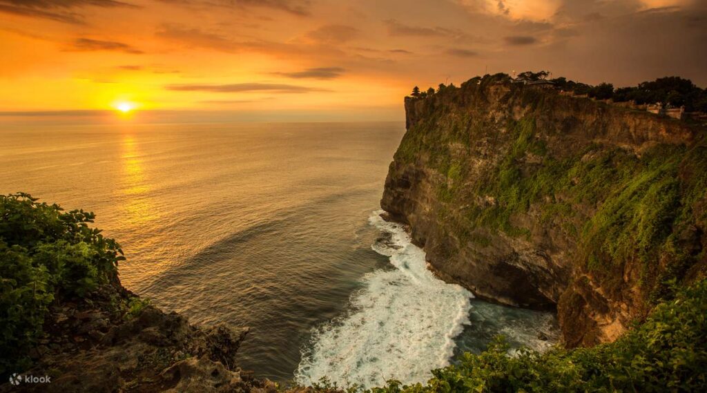 Bali couple tour watching sunset at Uluwatu Temple cliffside.