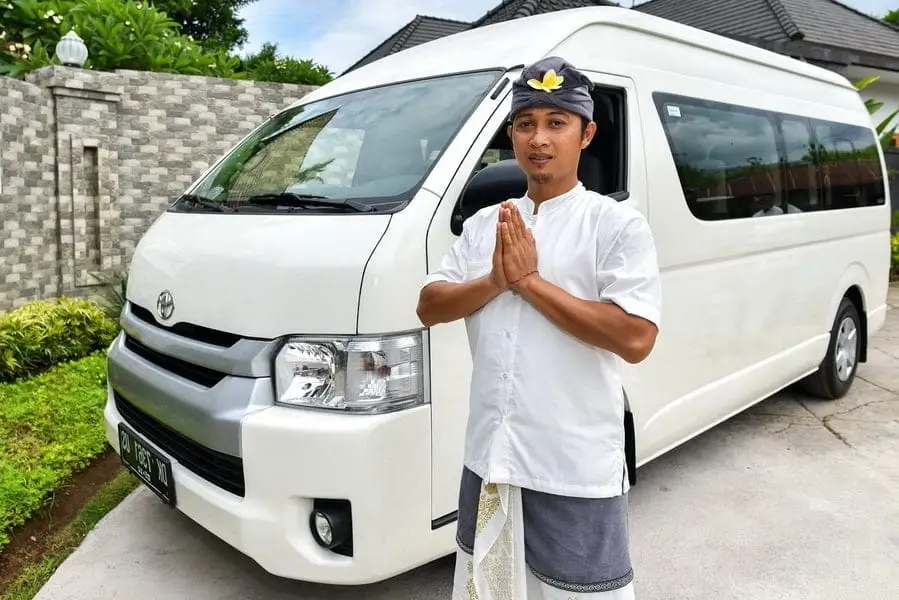 Professional Bali driver standing next to a private vehicle, ready for a Bali tour and travel journey.