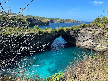 Stunning view of Broken Beach in Nusa Penida with turquoise waters and natural rock arch, included in Bali Tour Packages.
