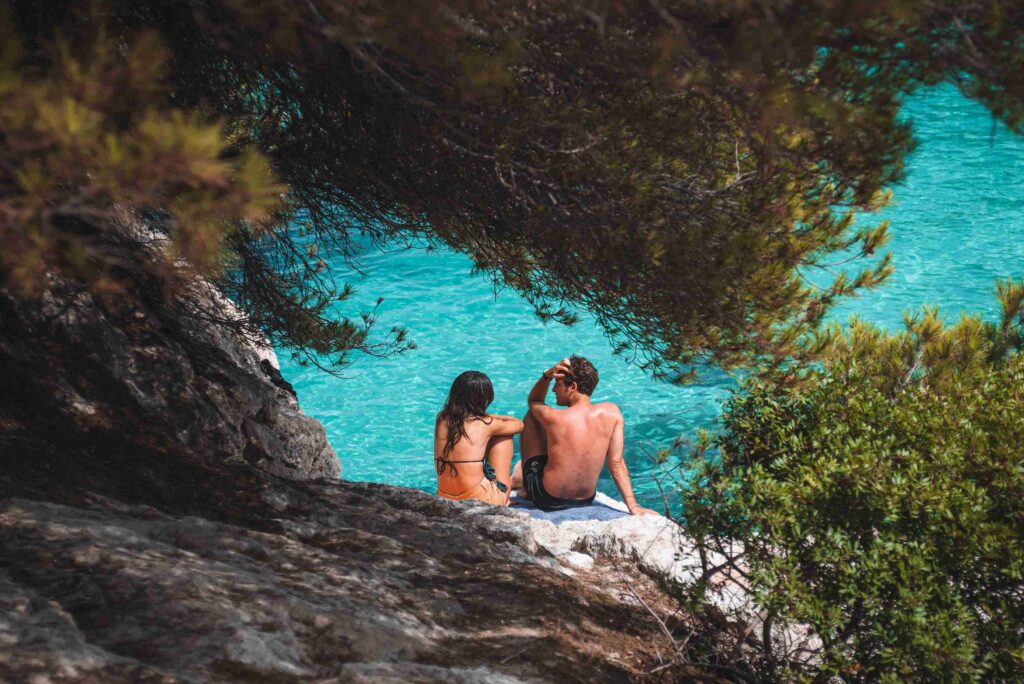 Romantic Bali tours – couple sitting by a turquoise natural pool, enjoying Bali’s hidden romantic spots.
