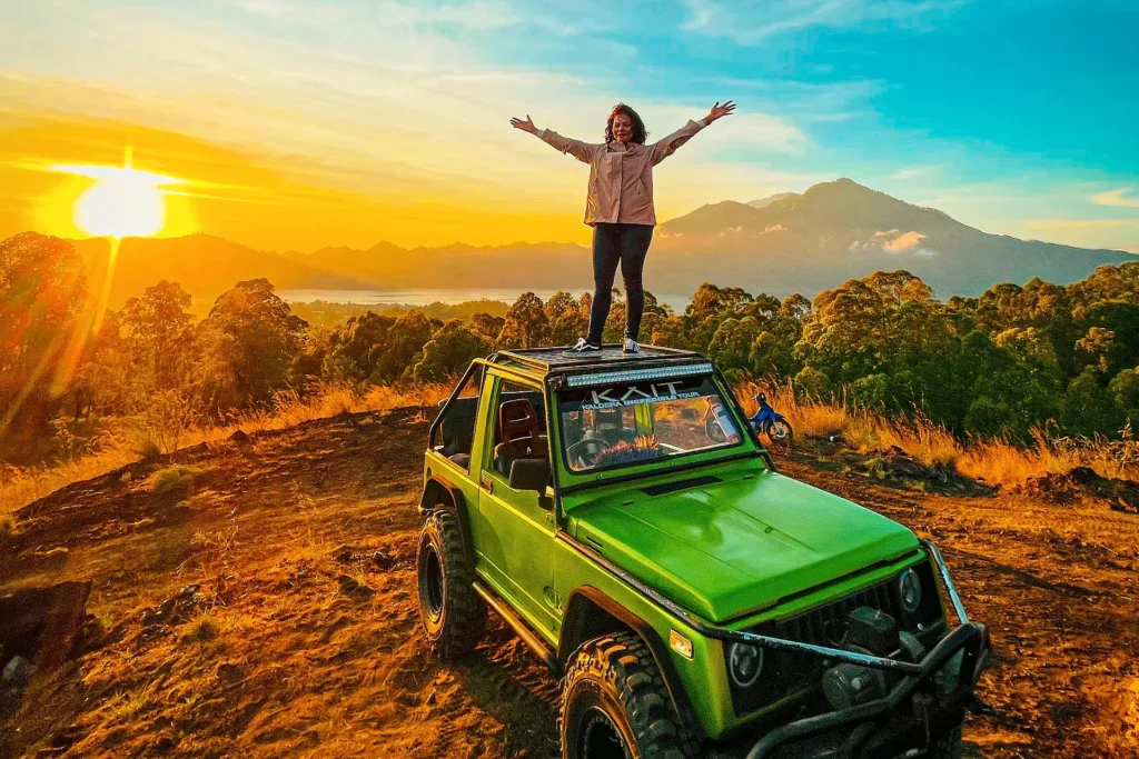 Tourist celebrating atop a jeep during a sunrise adventure in Bali, part of a Bali tour and travel package.