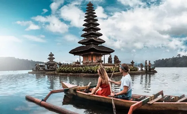 Bali couple tour exploring Ulun Danu Beratan Temple by the lake.