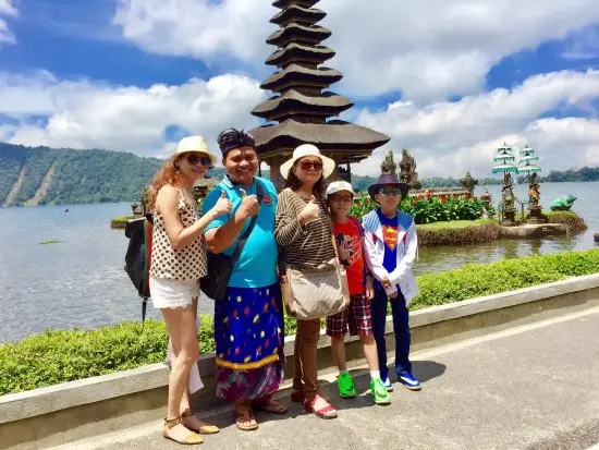 Bali guide with family travelers exploring Ulun Danu temple and lake scenery
