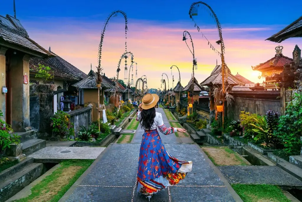 Tourist walking along a traditional Balinese street with penjor decorations on a Flexible Bali Tour.
