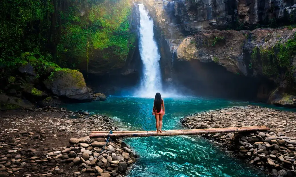 Traveler standing by a tropical waterfall surrounded by jungle during a Flexible Bali Tour.