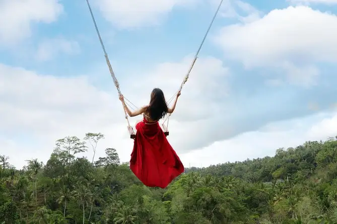Traveler enjoying Bali Adventure Tour on the famous Tegalalang swing overlooking rice terraces.