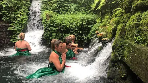 Happy family relaxing together under a tropical waterfall, creating unforgettable memories on their Bali Family Tour.