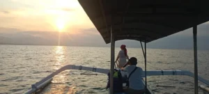 Romantic couple enjoying sunset dinner by the beach during their Bali honeymoon package by Bali Agung Tour.