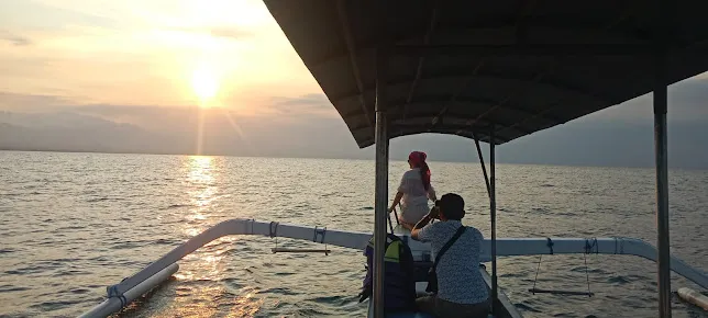 A family enjoying a boat ride during sunrise on a Bali Family Tour, capturing peaceful ocean moments together.