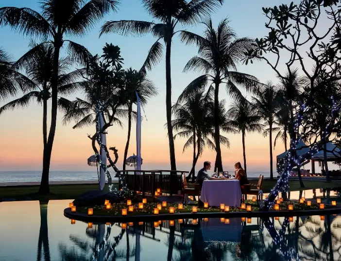 Sunset beachfront dinner experience featured in a Bali honeymoon package for romantic getaways.
