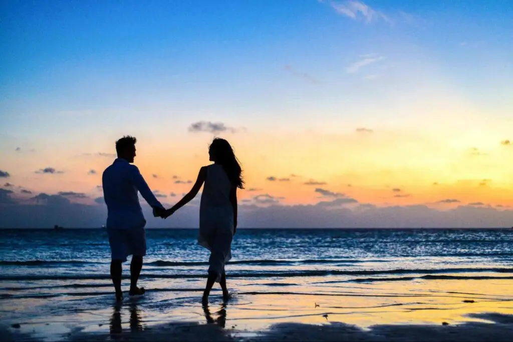 Couple enjoying a Seminyak sunset beach walk included in an affordable Bali honeymoon package.